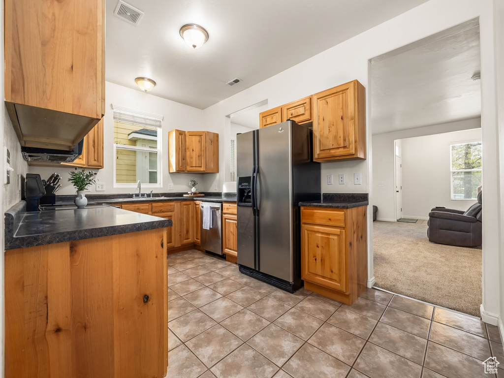 Kitchen featuring refrigerator with ice dispenser, visible vents, dark countertops, and dishwasher