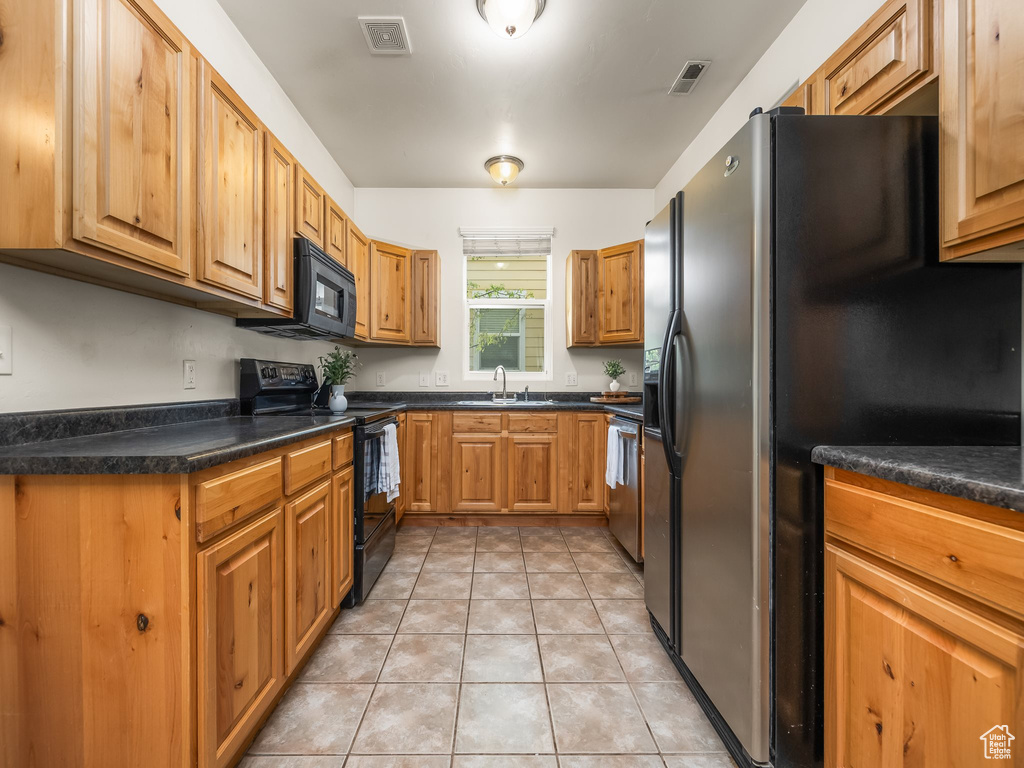 Kitchen with a sink, dark countertops, black appliances, and visible vents
