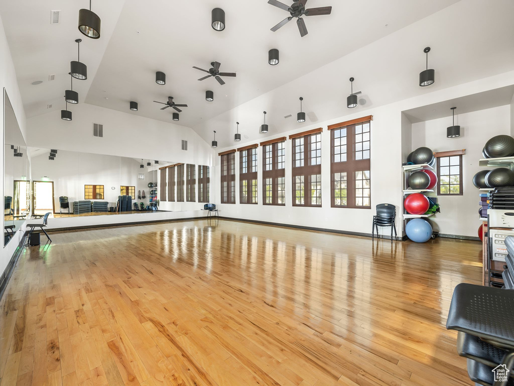 Workout area featuring visible vents, ceiling fan, wood finished floors, and high vaulted ceiling