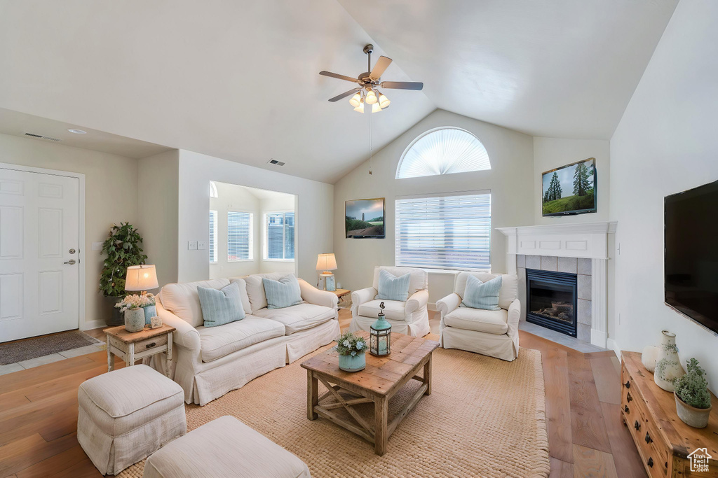 Living room featuring a ceiling fan, light wood finished floors, a tile fireplace, and visible vents