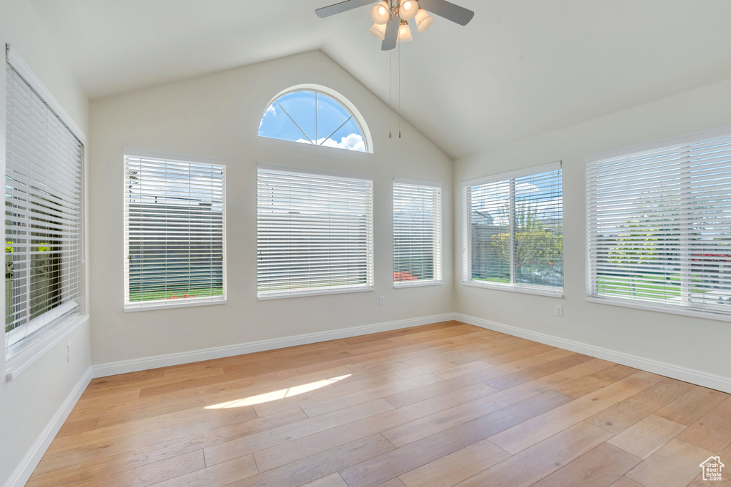 Unfurnished sunroom featuring baseboards, wood-type flooring, and vaulted ceiling