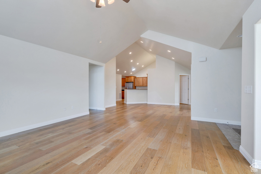 Unfurnished living room with ceiling fan, high vaulted ceiling, recessed lighting, baseboards, and light wood-type flooring
