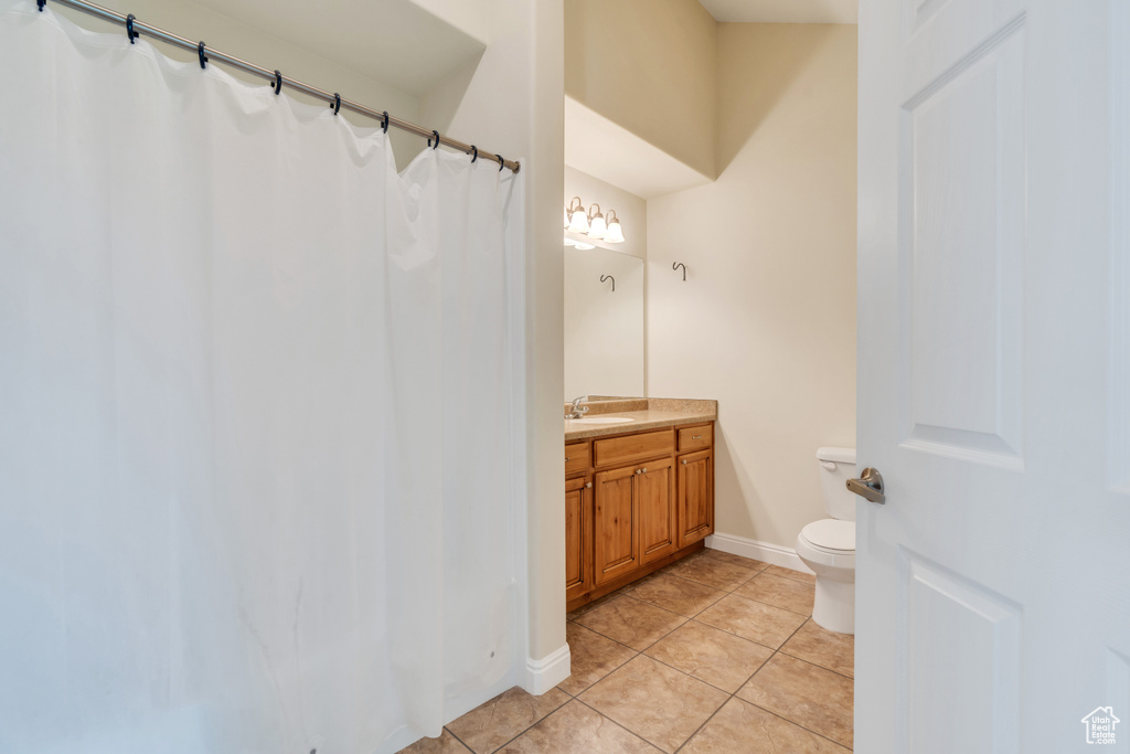 Full bath with vanity, tile patterned flooring, baseboards, and toilet