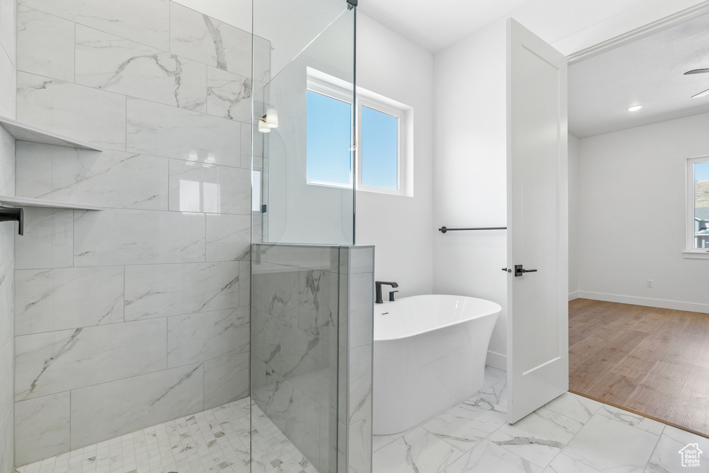 Bathroom with a healthy amount of sunlight, baseboards, tiled shower, and a freestanding bath