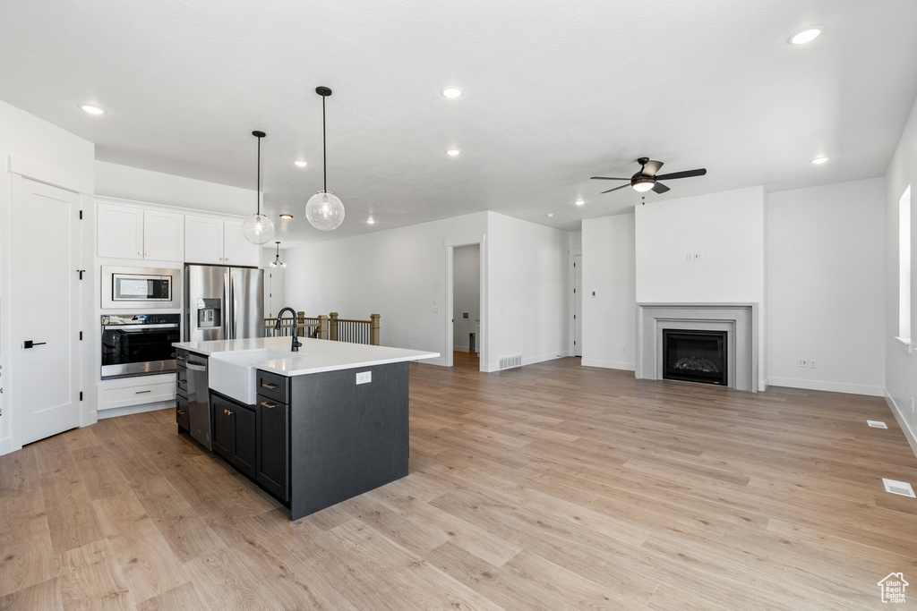 Kitchen with a ceiling fan, appliances with stainless steel finishes, a center island with sink, a sink, and recessed lighting