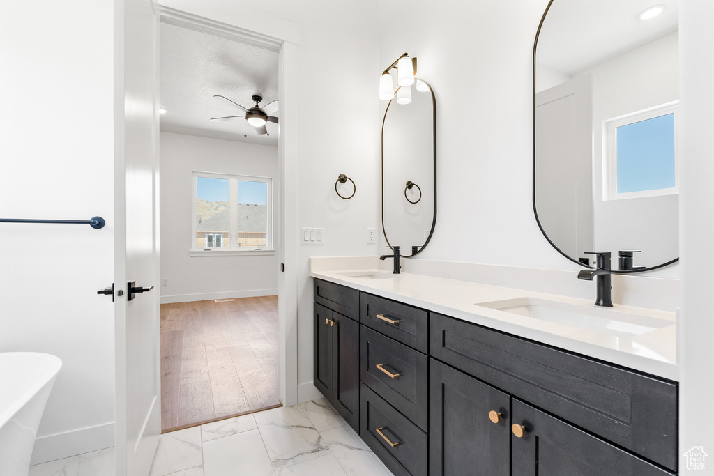 Bathroom featuring baseboards, a sink, ceiling fan, and double vanity