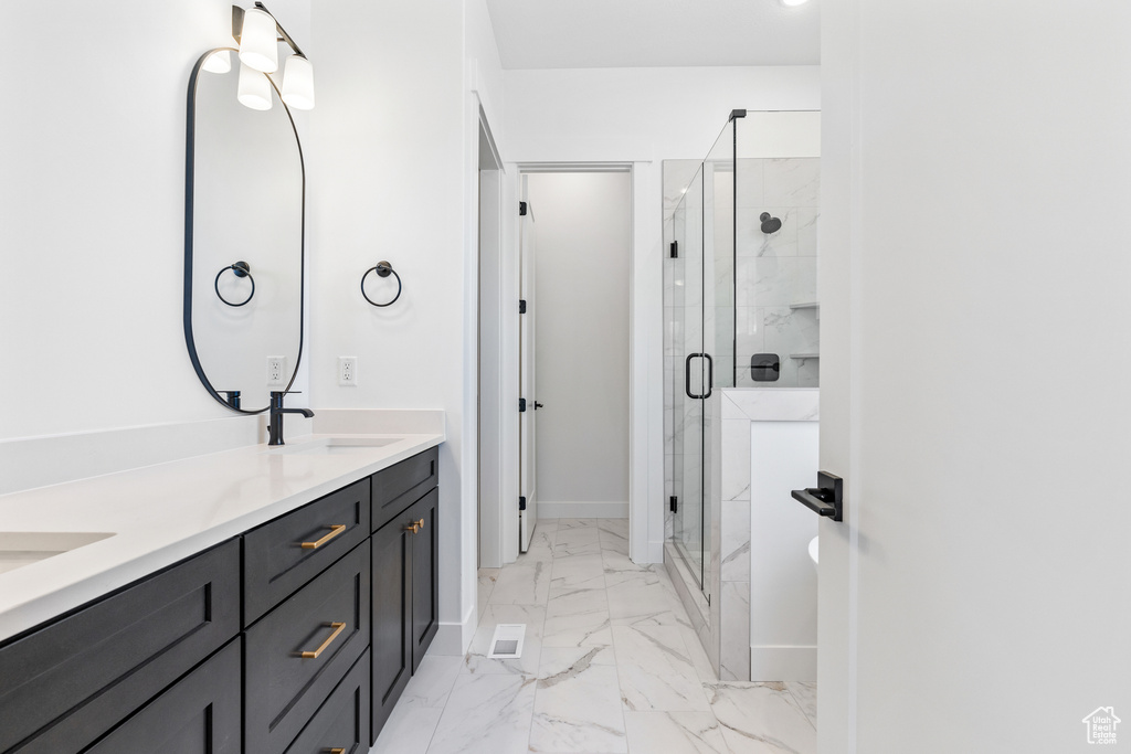 Full bathroom with a sink, double vanity, marble finish floor, baseboards, and a shower stall