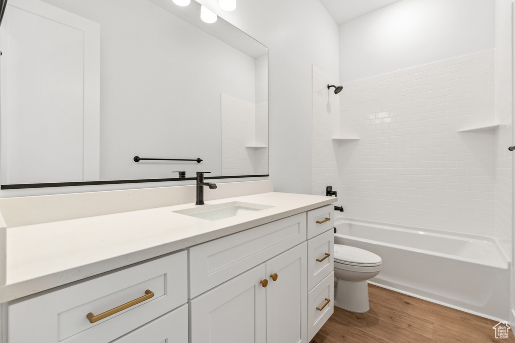 Bathroom featuring vanity, washtub / shower combination, wood finished floors, and toilet