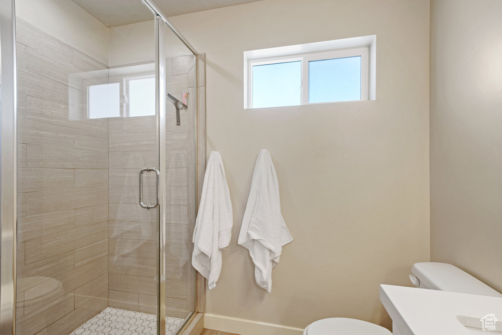 Bathroom featuring toilet, a stall shower, baseboards, and vanity