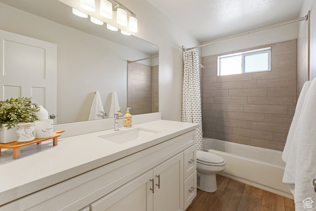 Full bath with vanity, shower / tub combo, wood finished floors, and toilet