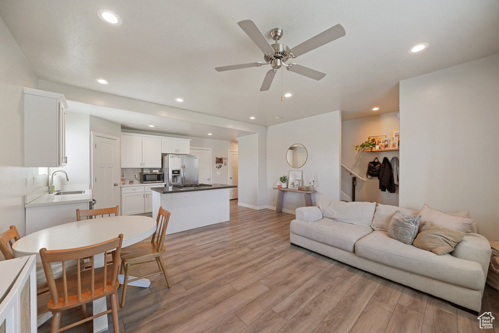 Living area with recessed lighting, baseboards, a ceiling fan, and light wood finished floors