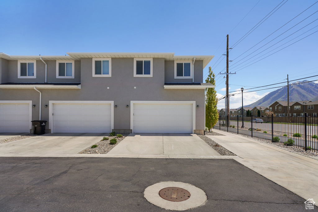 Townhome / multi-family property featuring fence, concrete driveway, stucco siding, and an attached garage