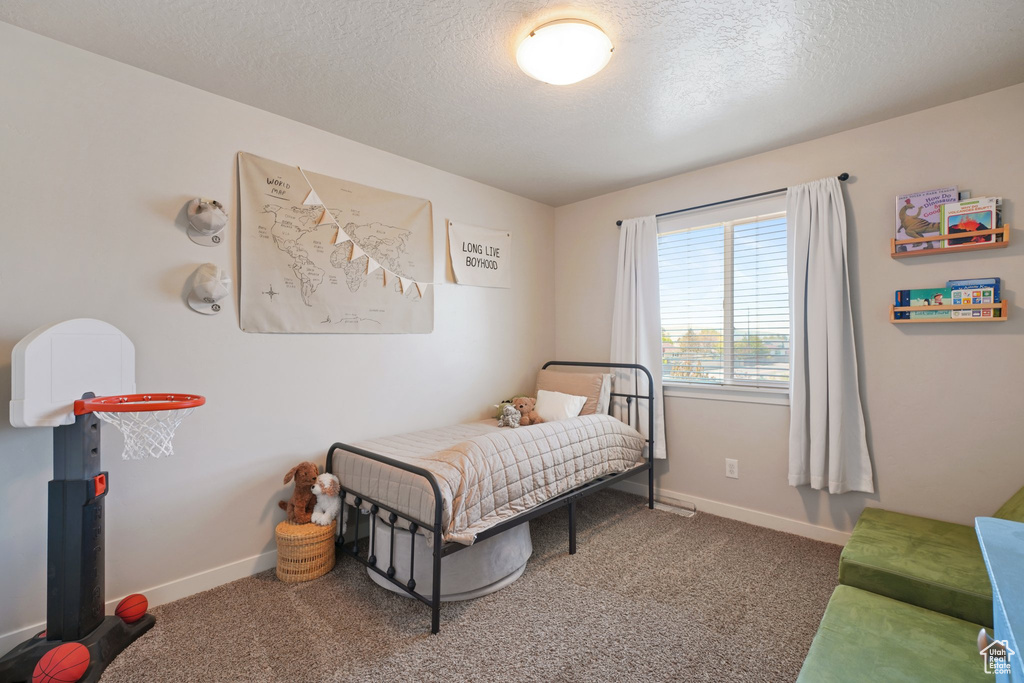 Carpeted bedroom featuring baseboards and a textured ceiling