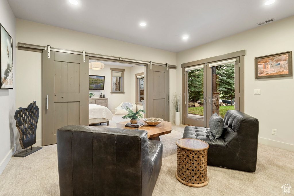 Living area featuring light colored carpet, baseboards, visible vents, and a barn door
