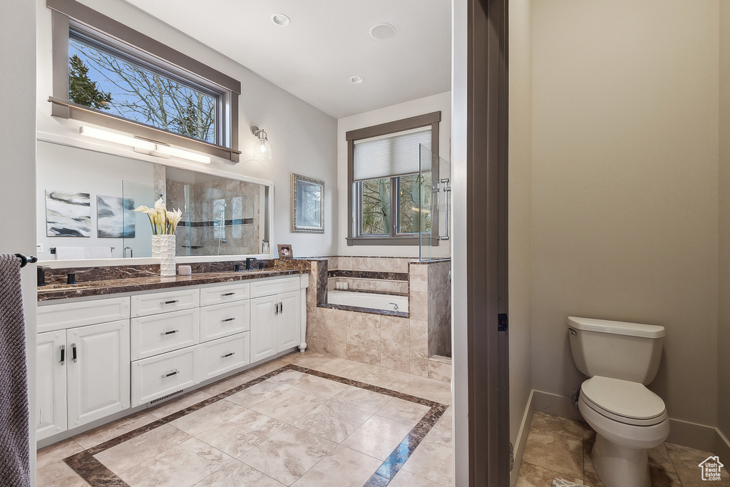 Bathroom featuring double vanity, toilet, recessed lighting, a bath, and a sink