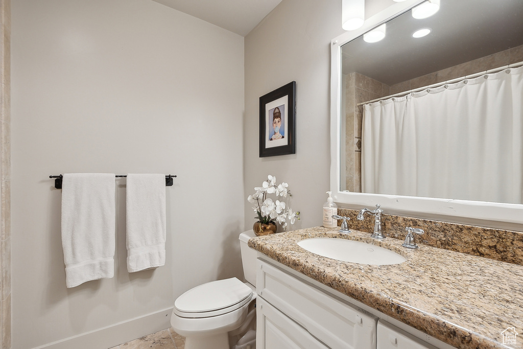 Bathroom featuring vanity, baseboards, curtained shower, and toilet