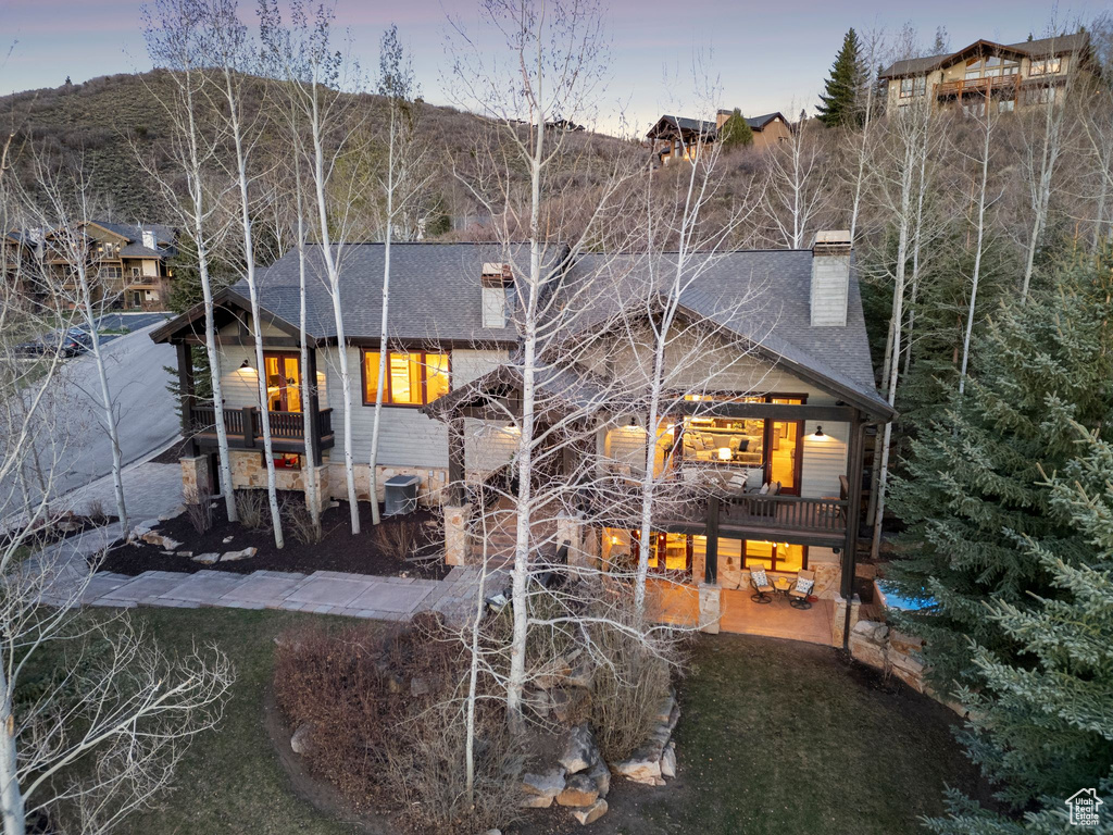 Rear view of house featuring a chimney, a shingled roof, and a patio area
