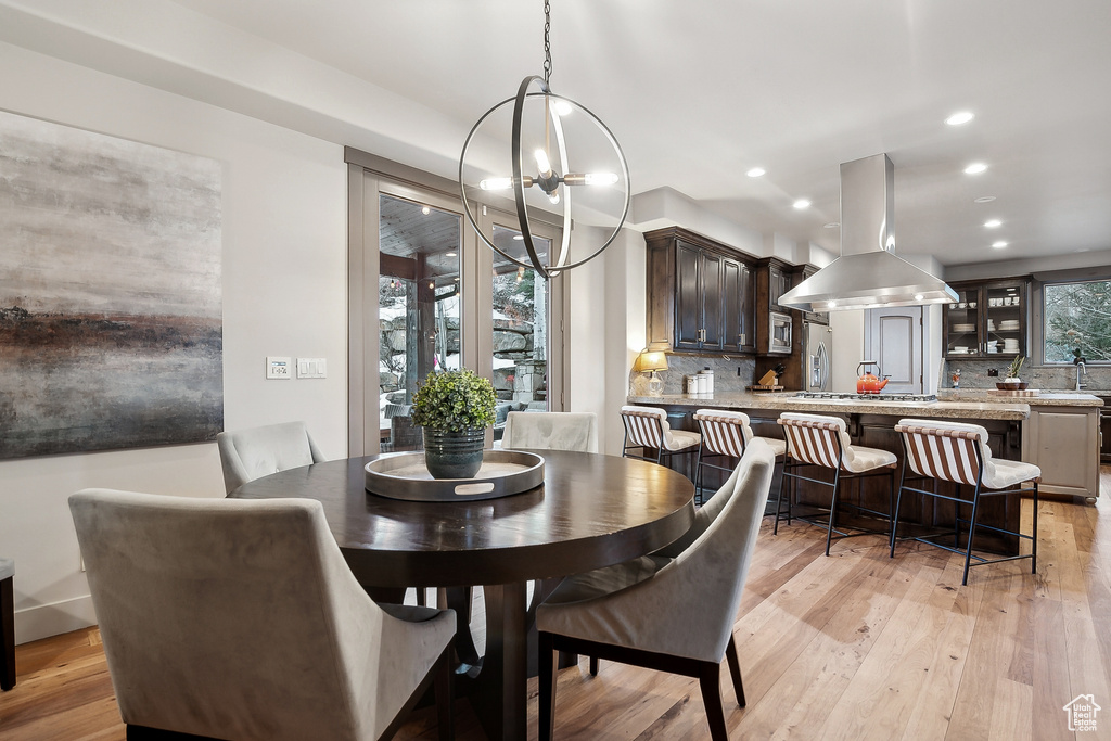 Dining area featuring light wood finished floors, recessed lighting, and a notable chandelier