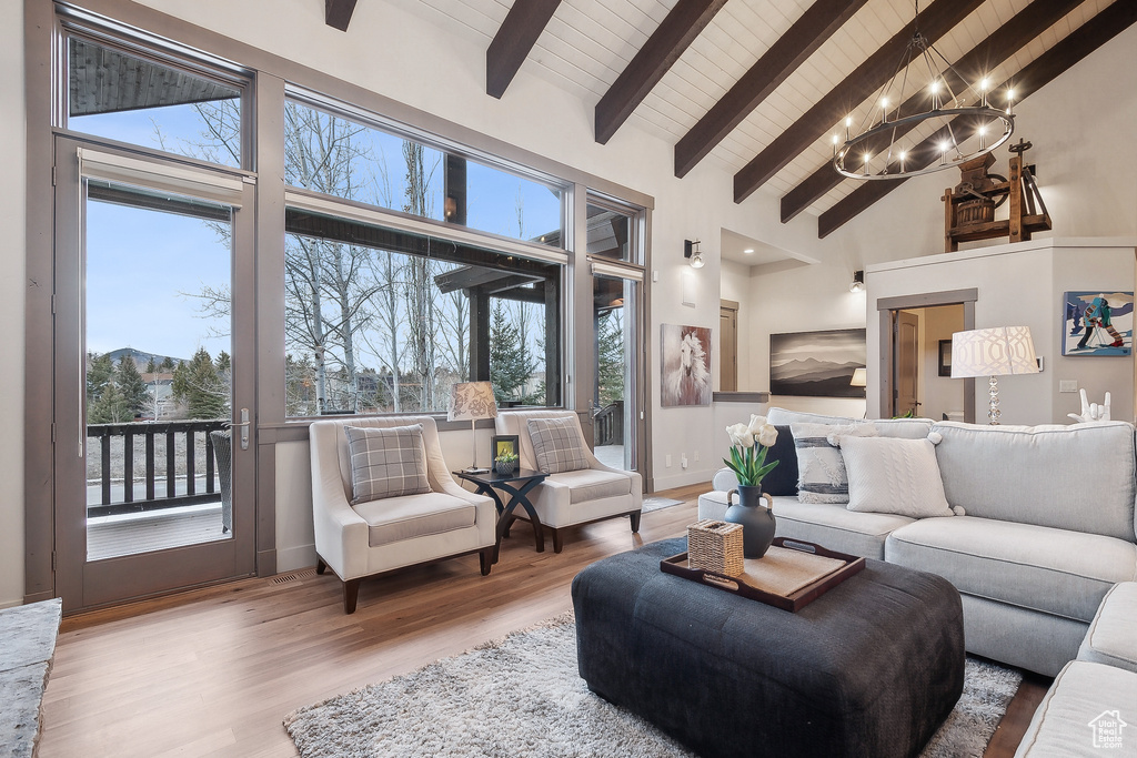 Living area with an inviting chandelier, beam ceiling, high vaulted ceiling, wooden ceiling, and wood finished floors