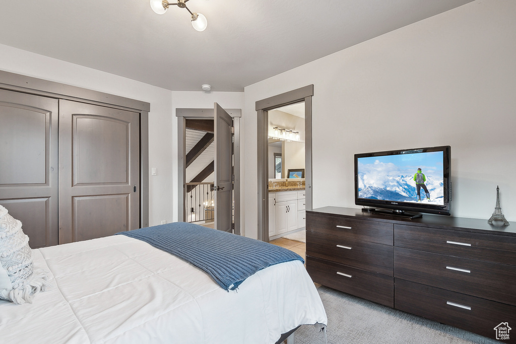 Bedroom featuring a closet, ensuite bathroom, and light colored carpet