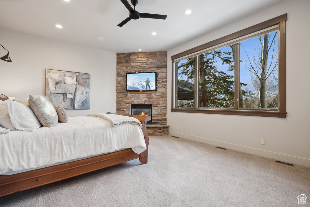 Carpeted bedroom featuring visible vents, baseboards, a stone fireplace, recessed lighting, and a ceiling fan