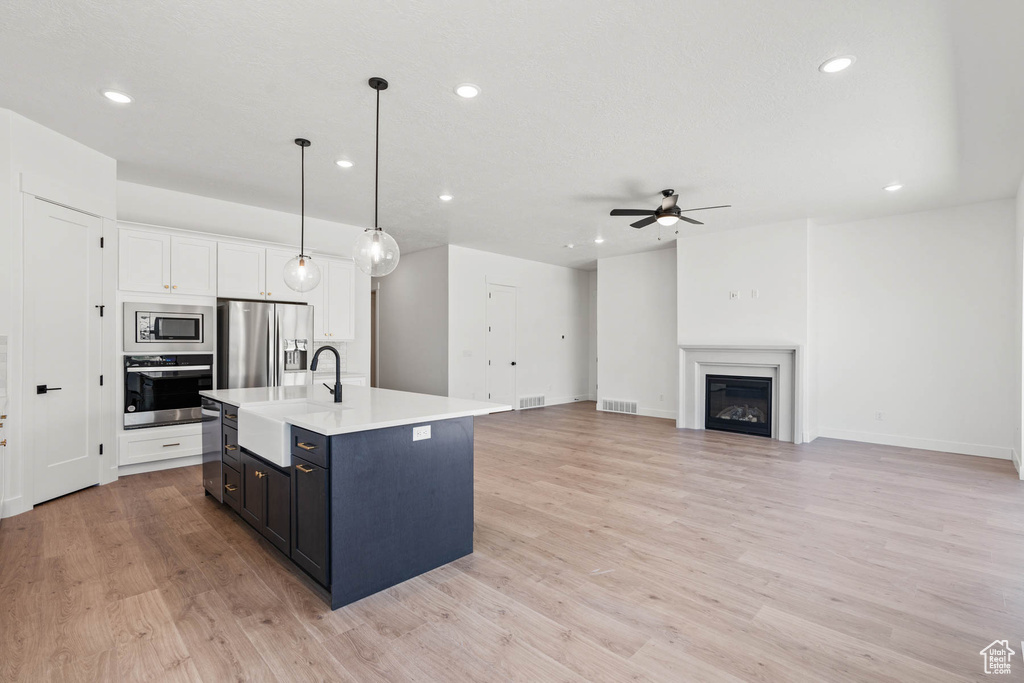 Kitchen with a ceiling fan, a sink, light countertops, stainless steel appliances, and recessed lighting