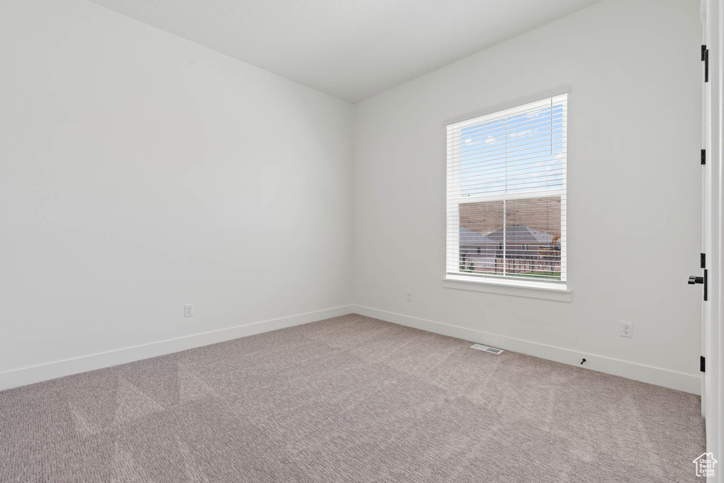 Unfurnished room featuring light colored carpet, baseboards, and visible vents