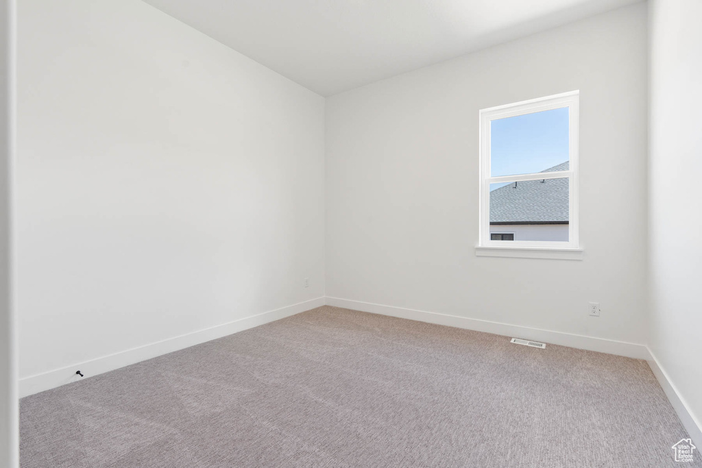 Spare room featuring baseboards, visible vents, and light carpet