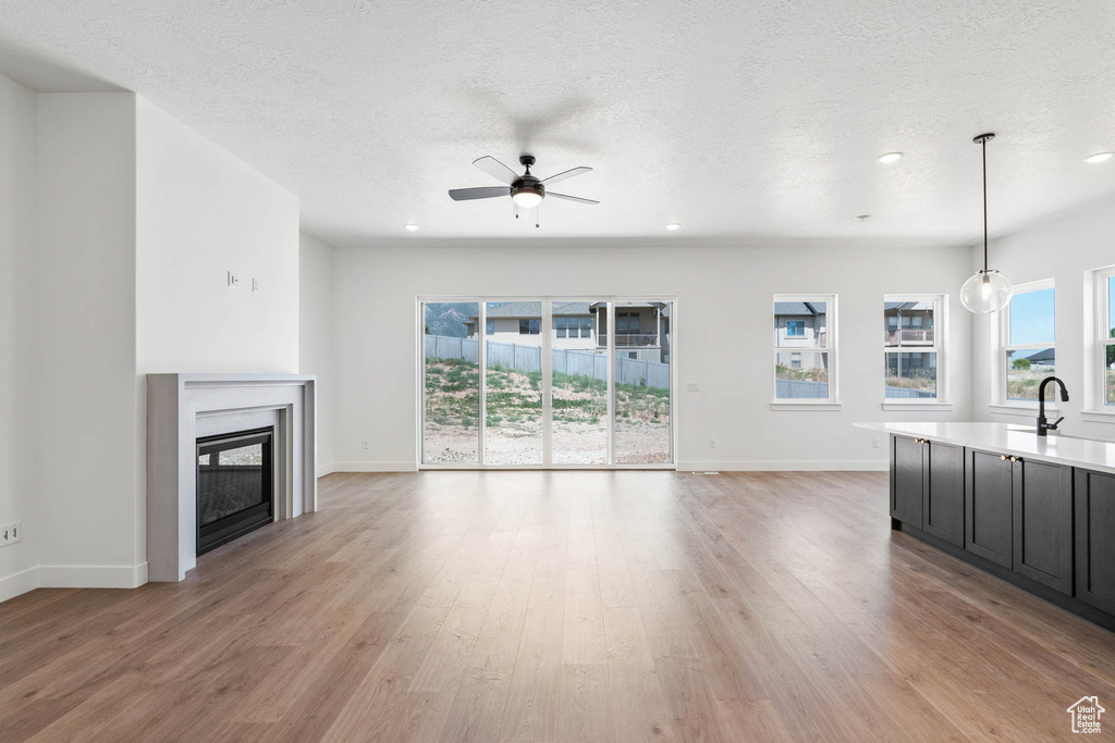 Unfurnished living room with baseboards, plenty of natural light, and a ceiling fan