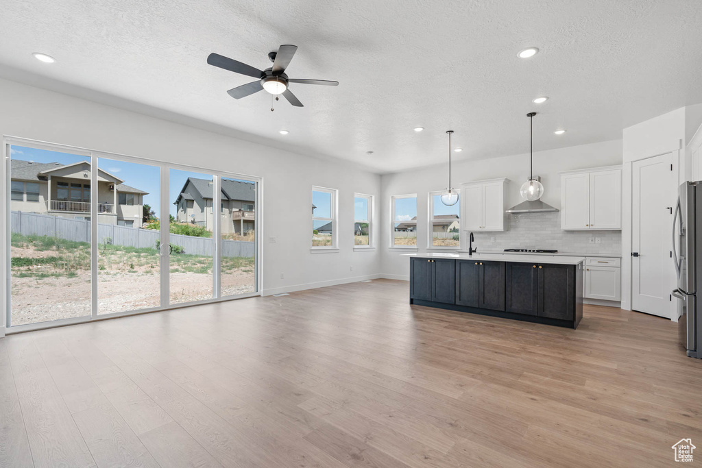 Kitchen featuring light wood-style floors, open floor plan, ceiling fan, light countertops, and white cabinetry