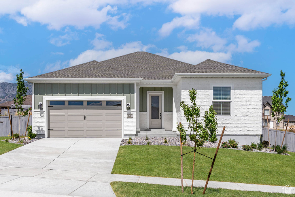 View of front facade featuring concrete driveway, fence, board and batten siding, and a garage