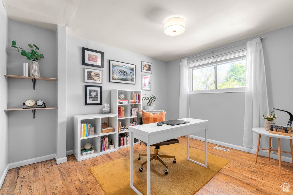 Office area with visible vents, baseboards, and hardwood / wood-style flooring