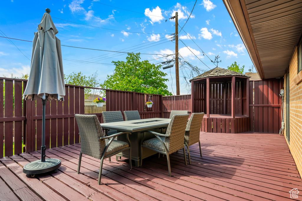 Deck featuring a gazebo, outdoor dining space, and a fenced backyard