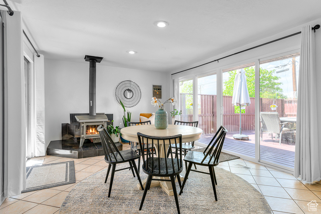 Dining space featuring recessed lighting, light tile patterned floors, and a wood stove