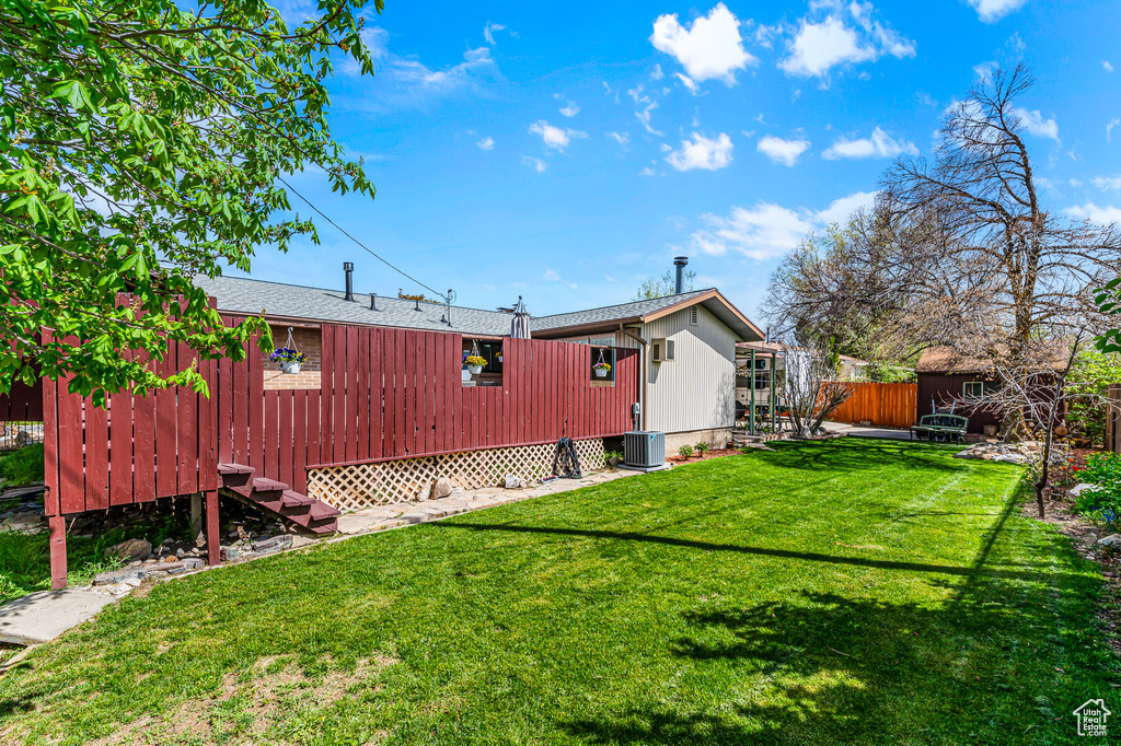 Exterior space with an outbuilding, central AC, a yard, and fence