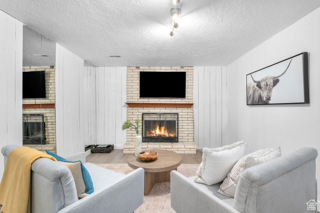 Living room featuring a textured ceiling, a fireplace, and wood finished floors