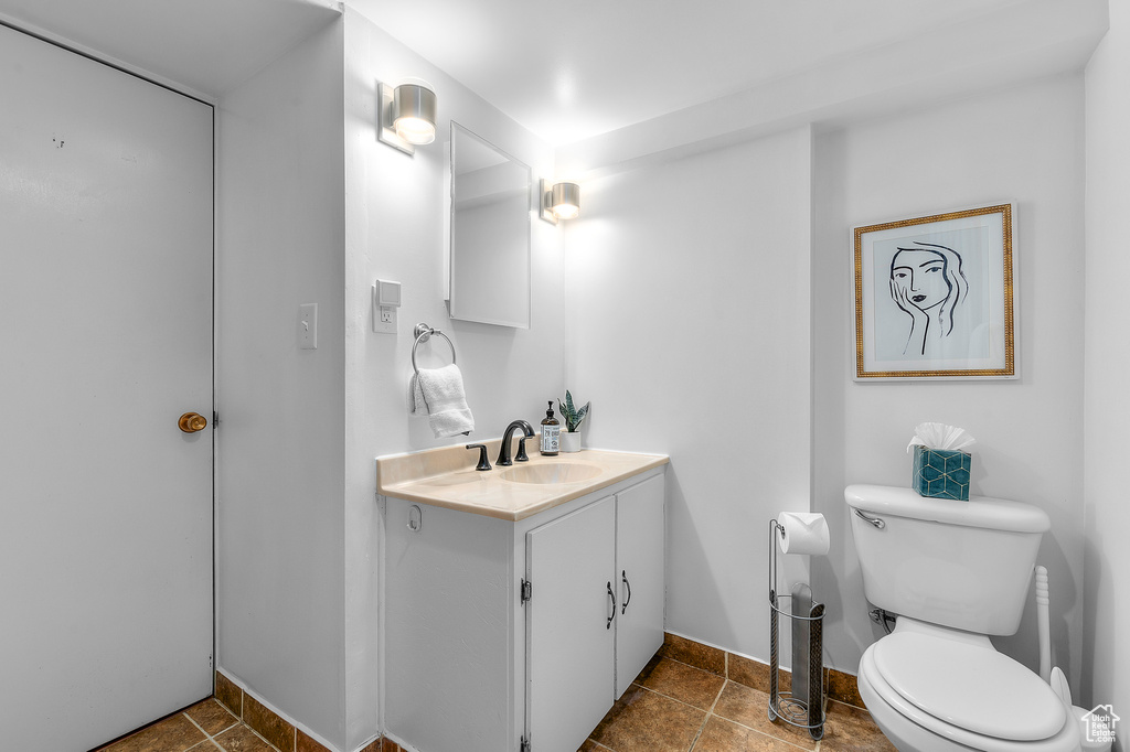 Half bath featuring vanity, baseboards, tile patterned floors, and toilet