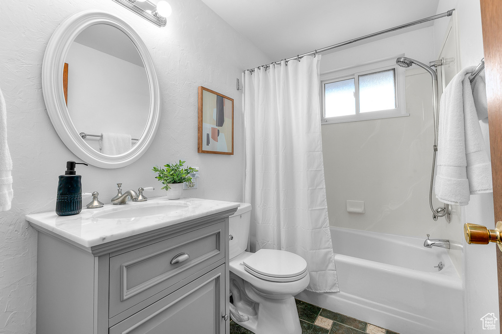 Full bathroom with vanity, shower / tub combo, and toilet