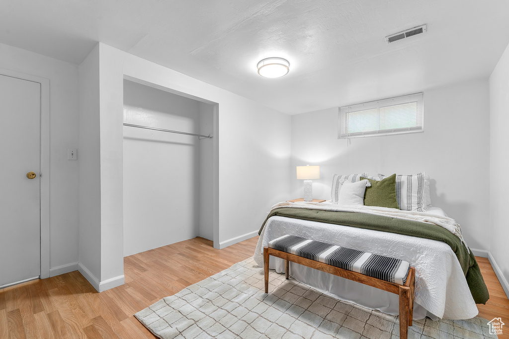 Bedroom featuring a closet, baseboards, visible vents, and light wood-type flooring