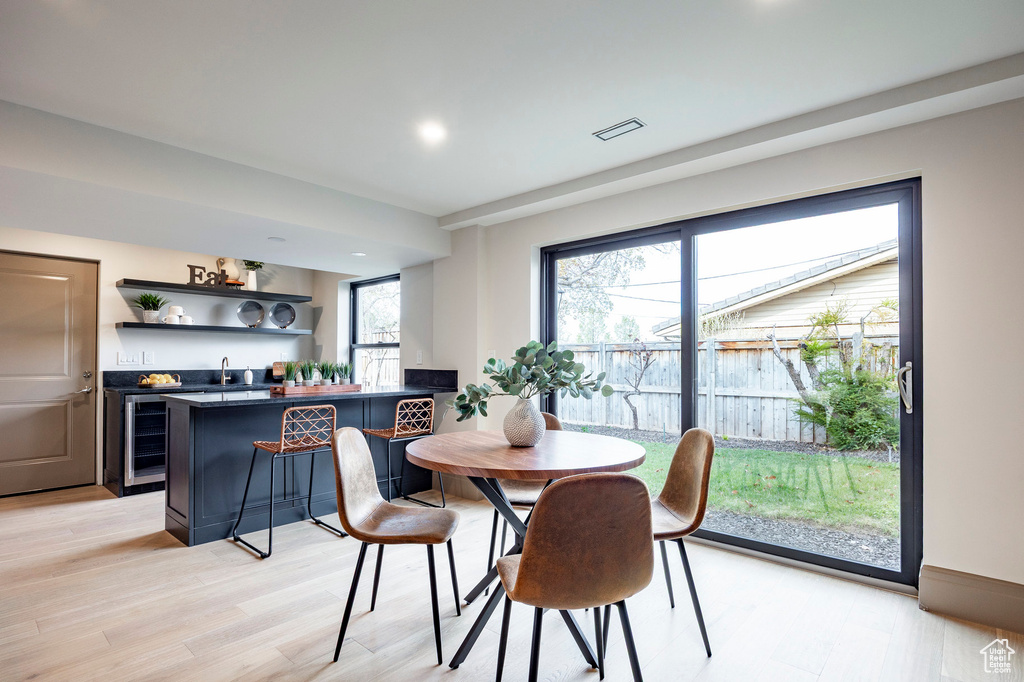 Dining room featuring light wood-style floors, beverage cooler, and wet bar