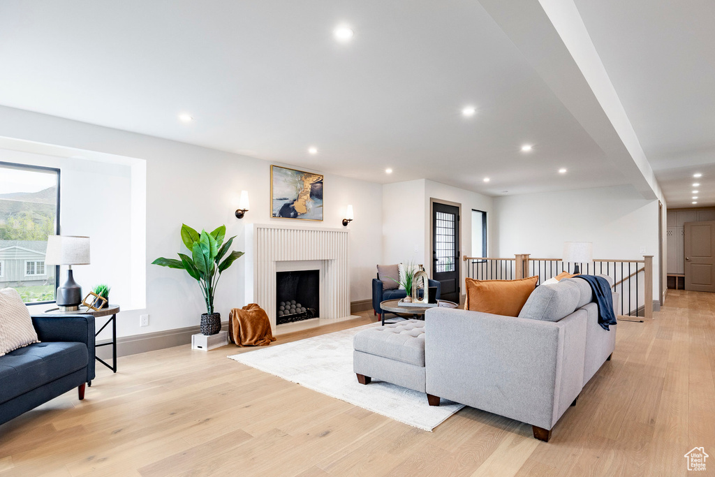 Living area with recessed lighting, baseboards, a fireplace with flush hearth, and light wood-type flooring