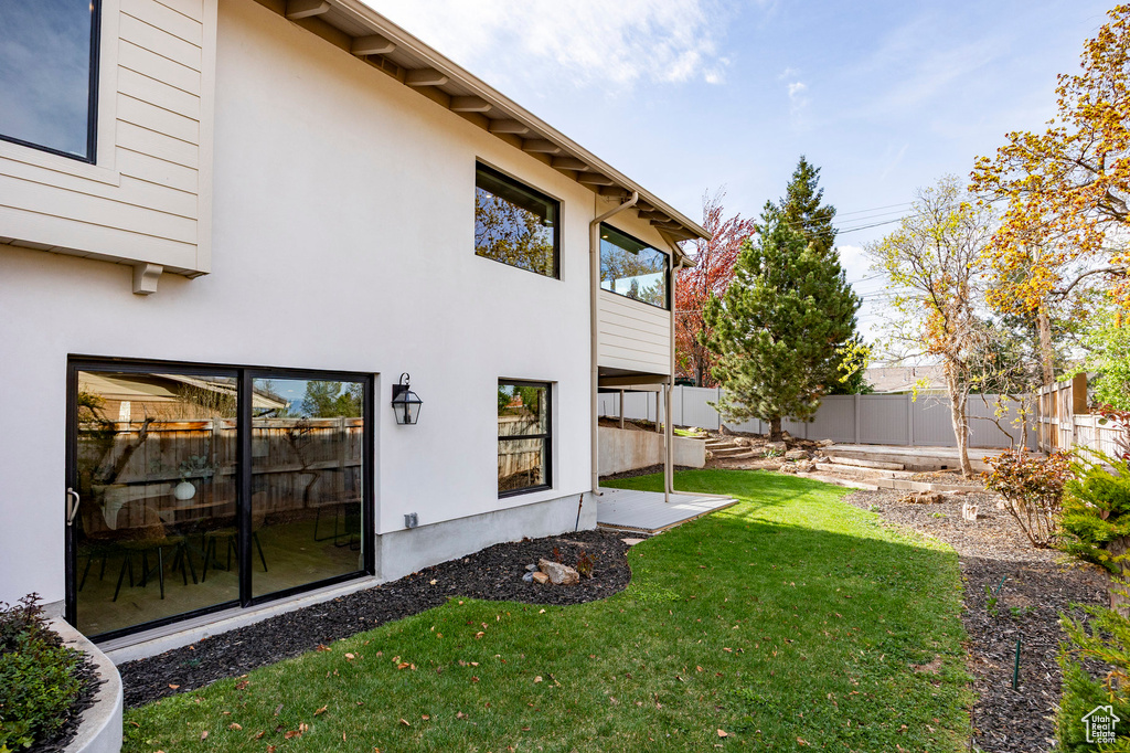 Exterior space featuring a fenced backyard, stucco siding, and a yard