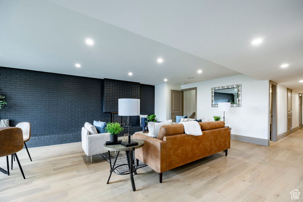 Living area with light wood-style floors, recessed lighting, and brick wall