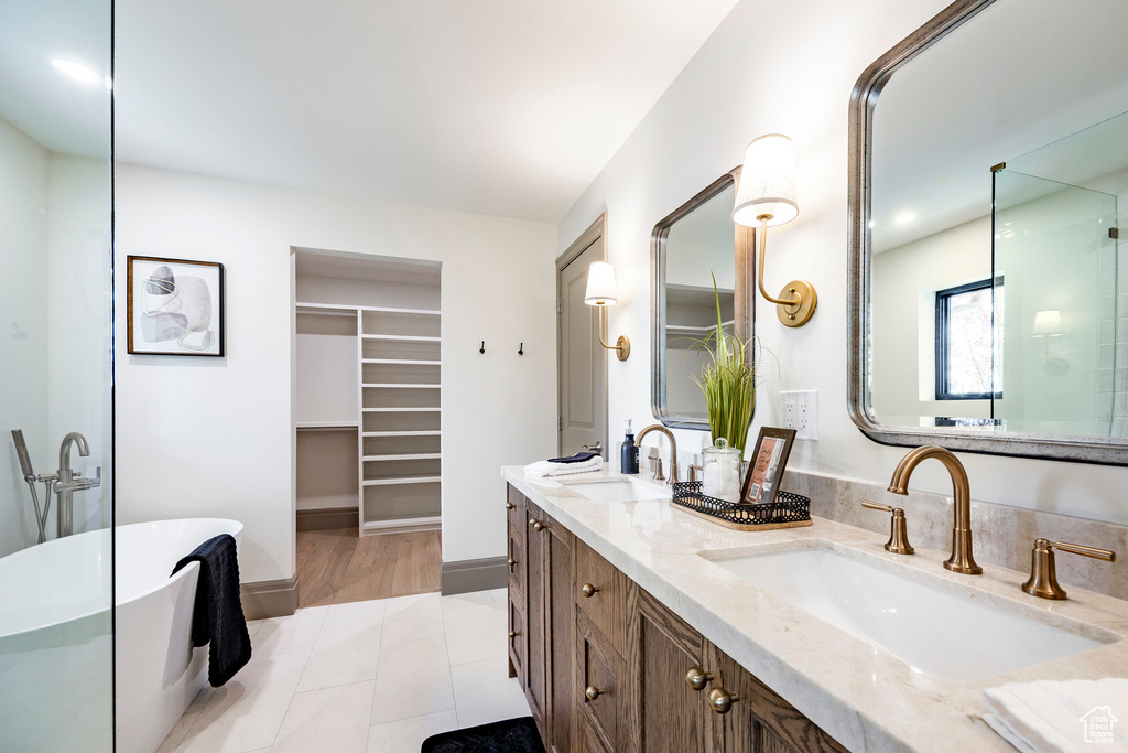 Full bathroom with a sink, a walk in closet, double vanity, and a freestanding bath