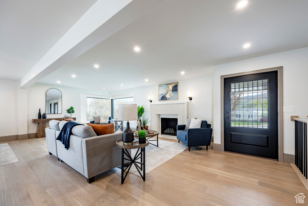 Living room featuring recessed lighting, baseboards, a fireplace with flush hearth, and light wood-style floors