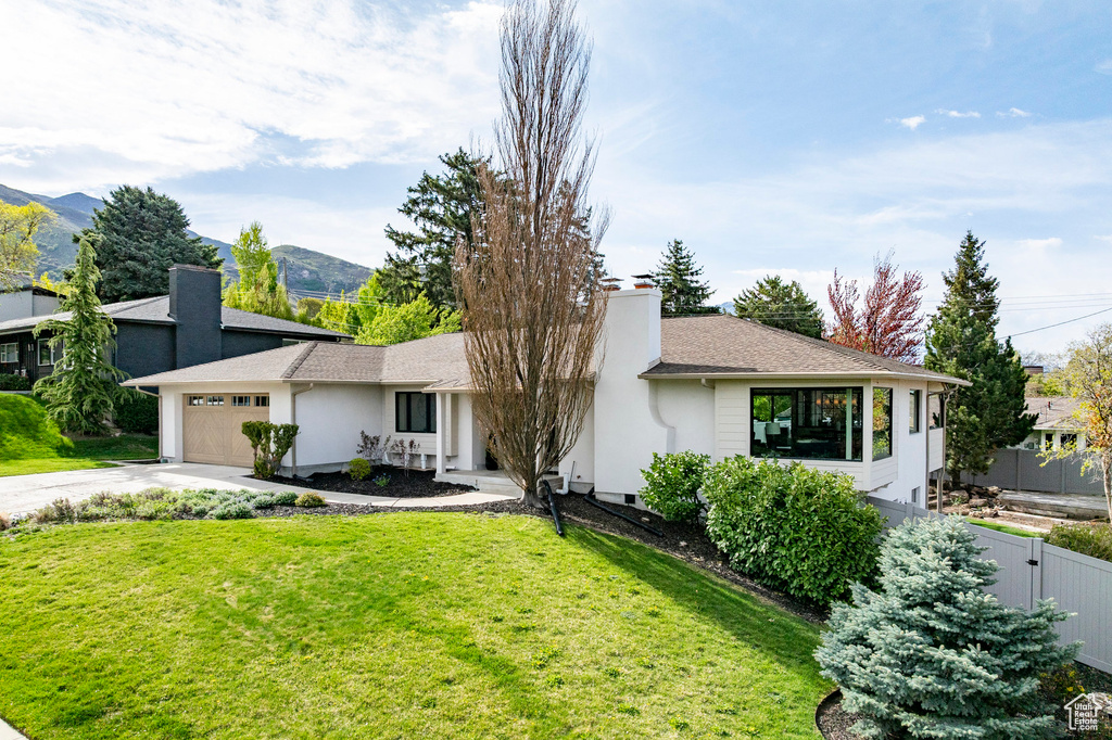 Single story home featuring a garage, fence, a front yard, a chimney, and driveway