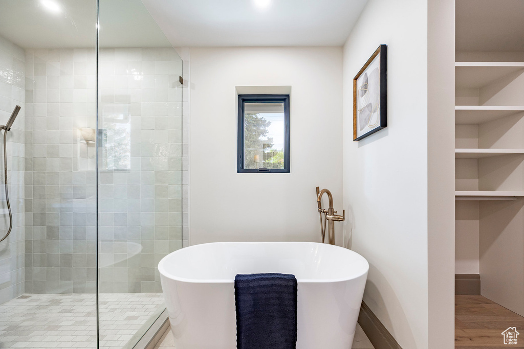 Bathroom with built in shelves, baseboards, a freestanding tub, wood finished floors, and a stall shower