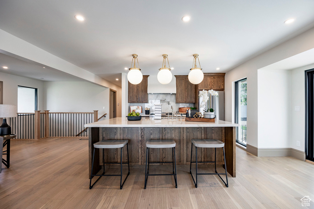 Kitchen with light countertops, recessed lighting, light wood-type flooring, and high quality fridge