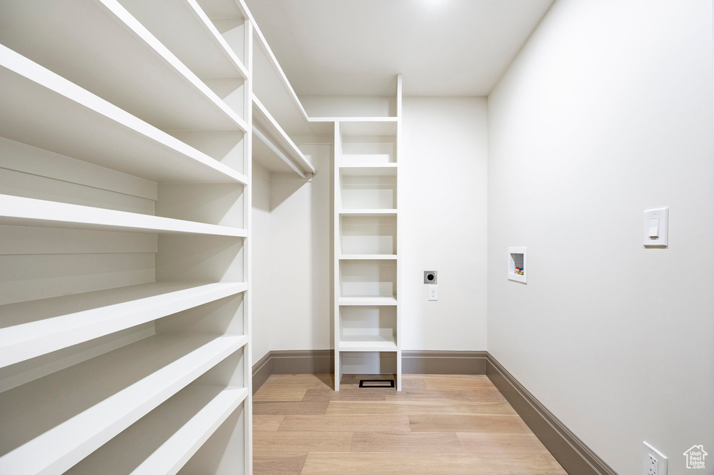 Walk in closet with light wood finished floors