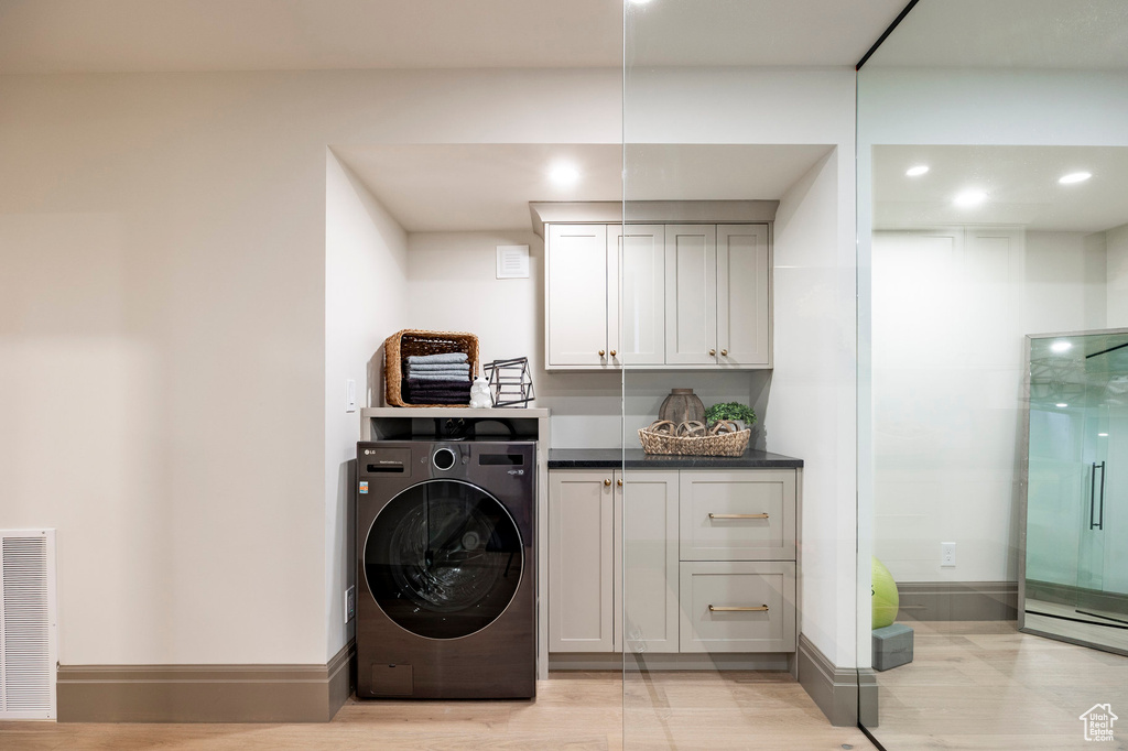 Laundry room with cabinet space, light wood-style flooring, recessed lighting, washer / dryer, and visible vents